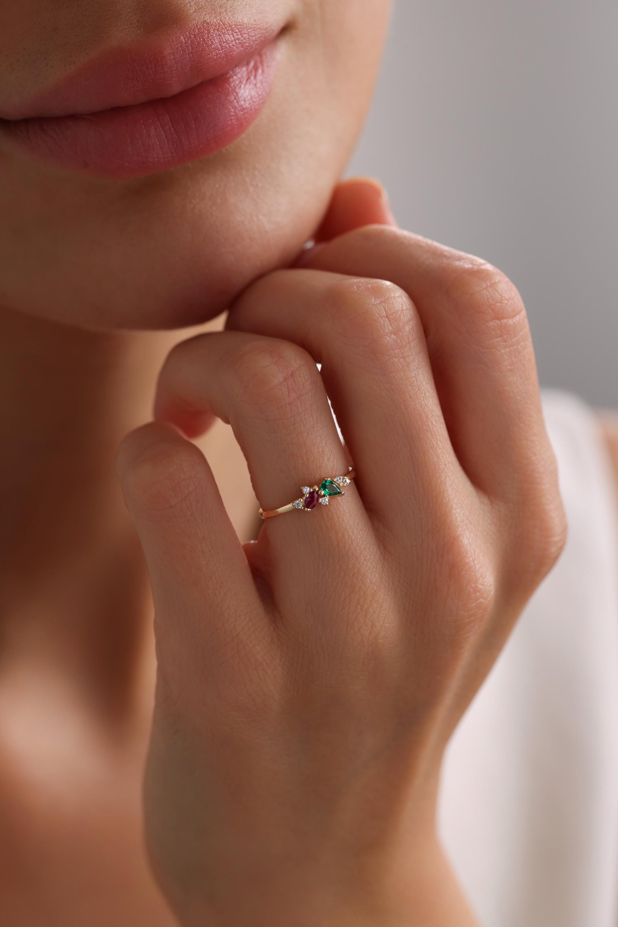 May include: A gold ring with a cluster of small diamonds, a green emerald, and a red ruby.